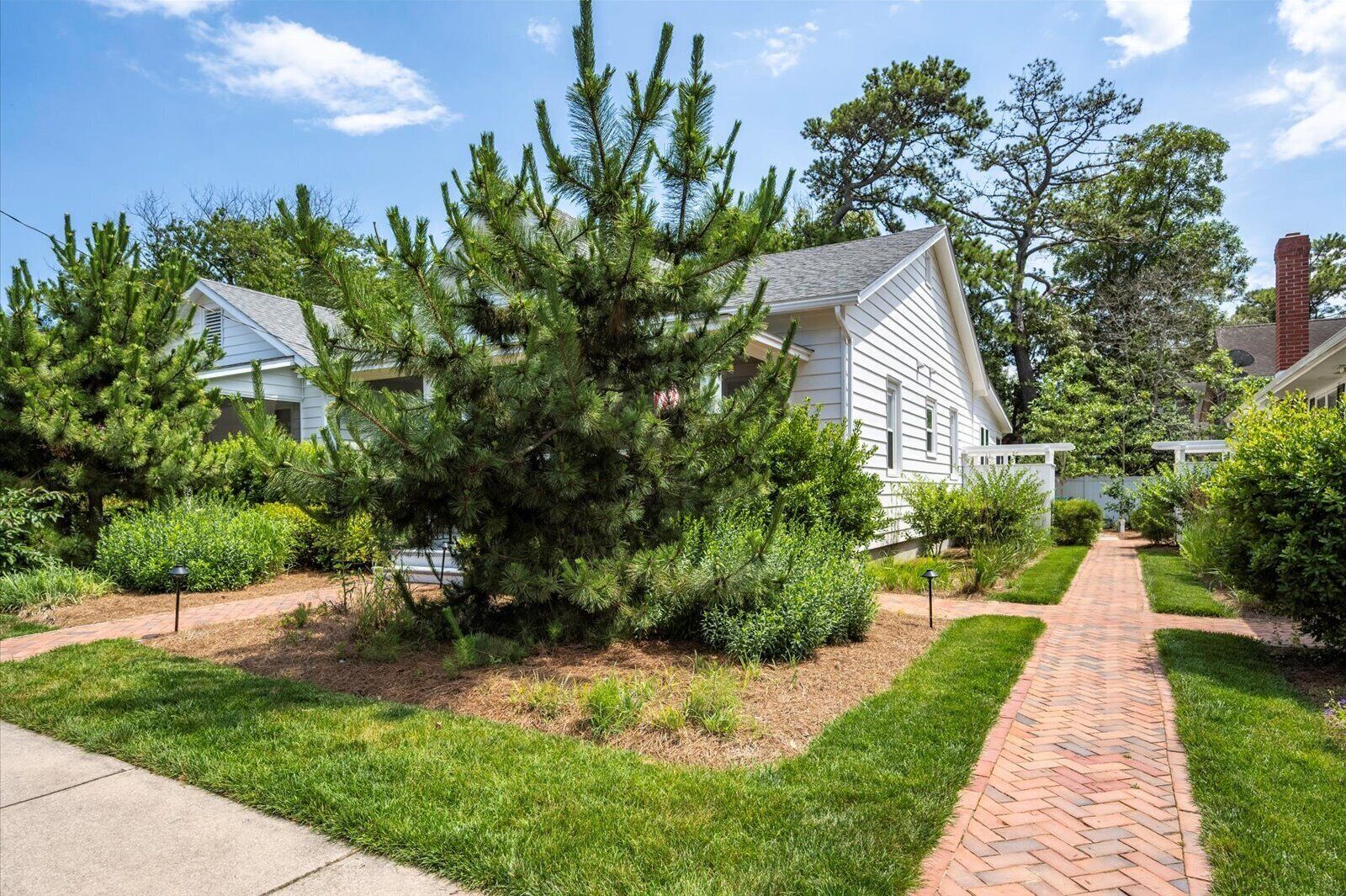 A residential area with a paved walkway, well-maintained lawns, and mature trees.