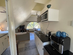 A compact kitchen with a microwave, coffee maker, and sink.