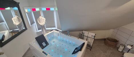 A modern bathroom with a large bathtub, a toilet, and a shower area.