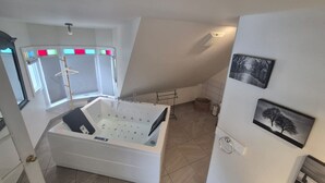Ein modernes Badezimmer mit einer freistehenden Badewanne, einem Handtuchhalter und einem Fenster mit Jalousien.