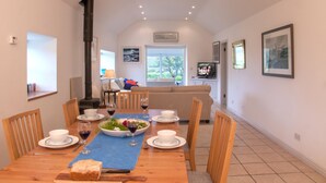 A dining area with a wooden table set for a meal, a fireplace, and a view of the outdoors. - Beautiful views to Inisbofin (Cleggan)