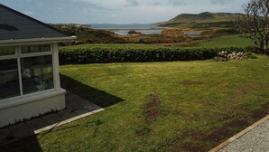 A house with a conservatory, a grassy yard, and a view of a lake and hills. - Beautiful views to Inisbofin (Cleggan)