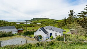 A white house with a black roof, surrounded by a gravel driveway and a blue gate. - Beautiful views to Inisbofin (Cleggan)