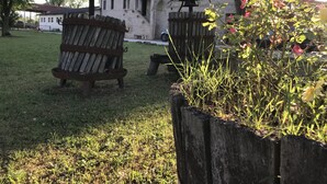 Two rustic wooden barrels in a grassy outdoor area with a building in the background.