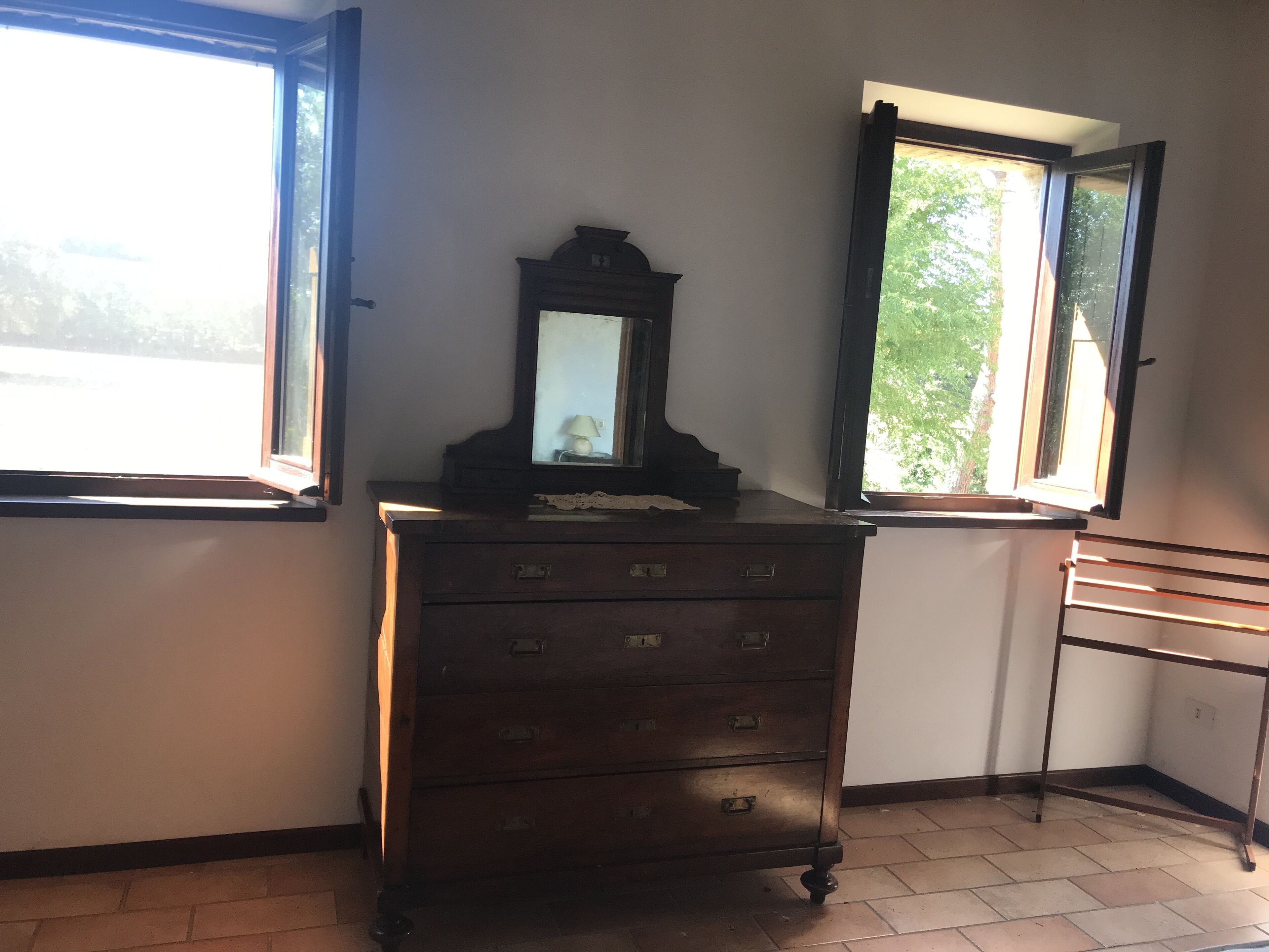 A corner room with a wooden dresser, a mirror, and two windows.