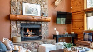 A cozy living room with a stone fireplace, a comfortable sofa, and a wooden TV shelf.