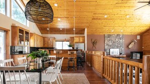 A spacious kitchen with wooden cabinets, a dining area with white chairs, and a stone accent wall.