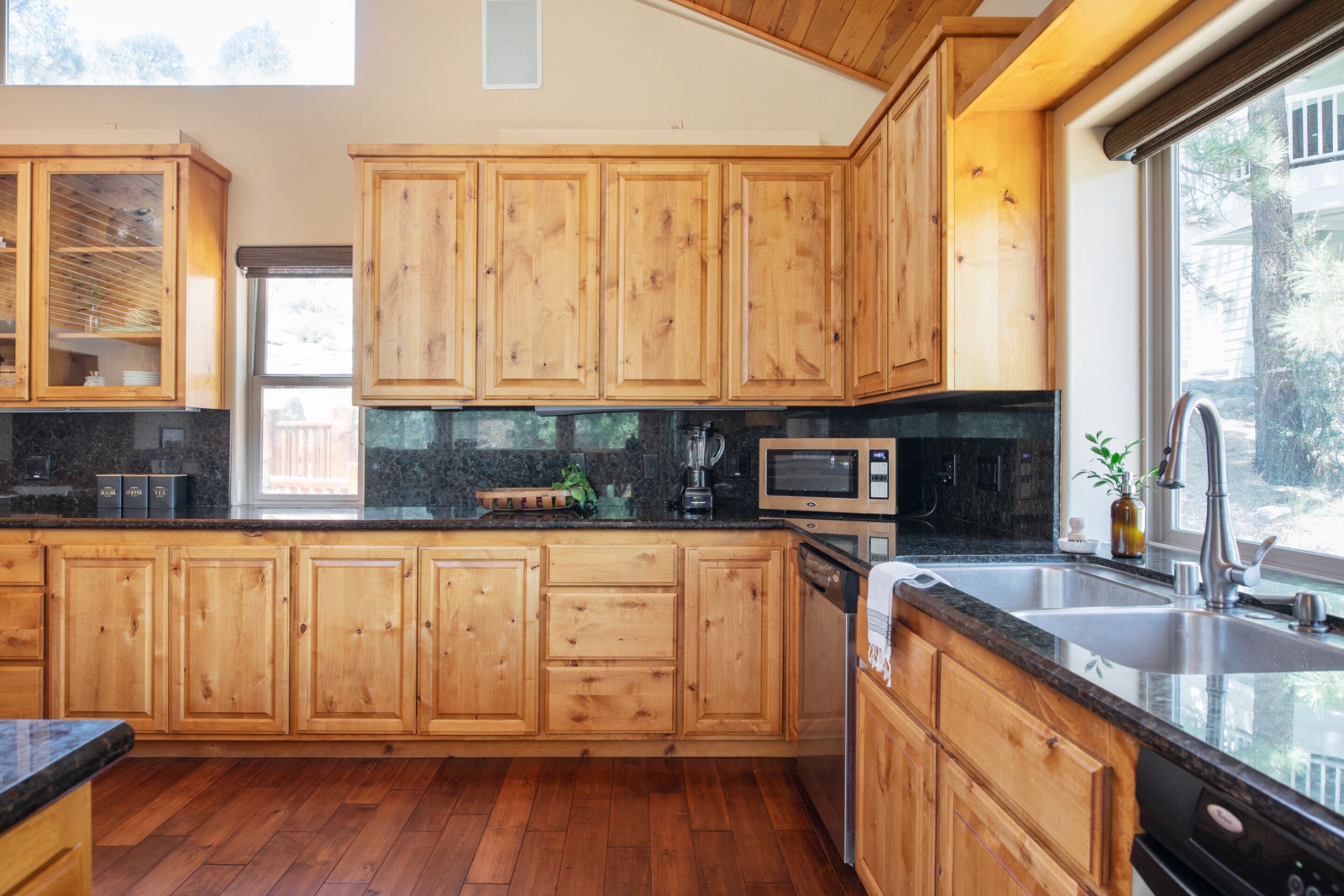 A modern kitchen with wooden cabinets, a granite countertop, a built-in microwave, and a large window providing natural light.