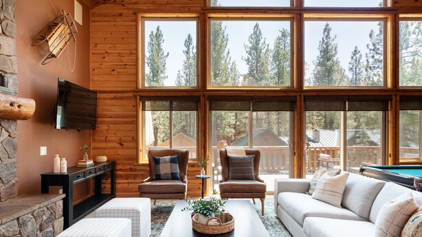 A cozy living room with a fireplace, large windows, and a pool table.