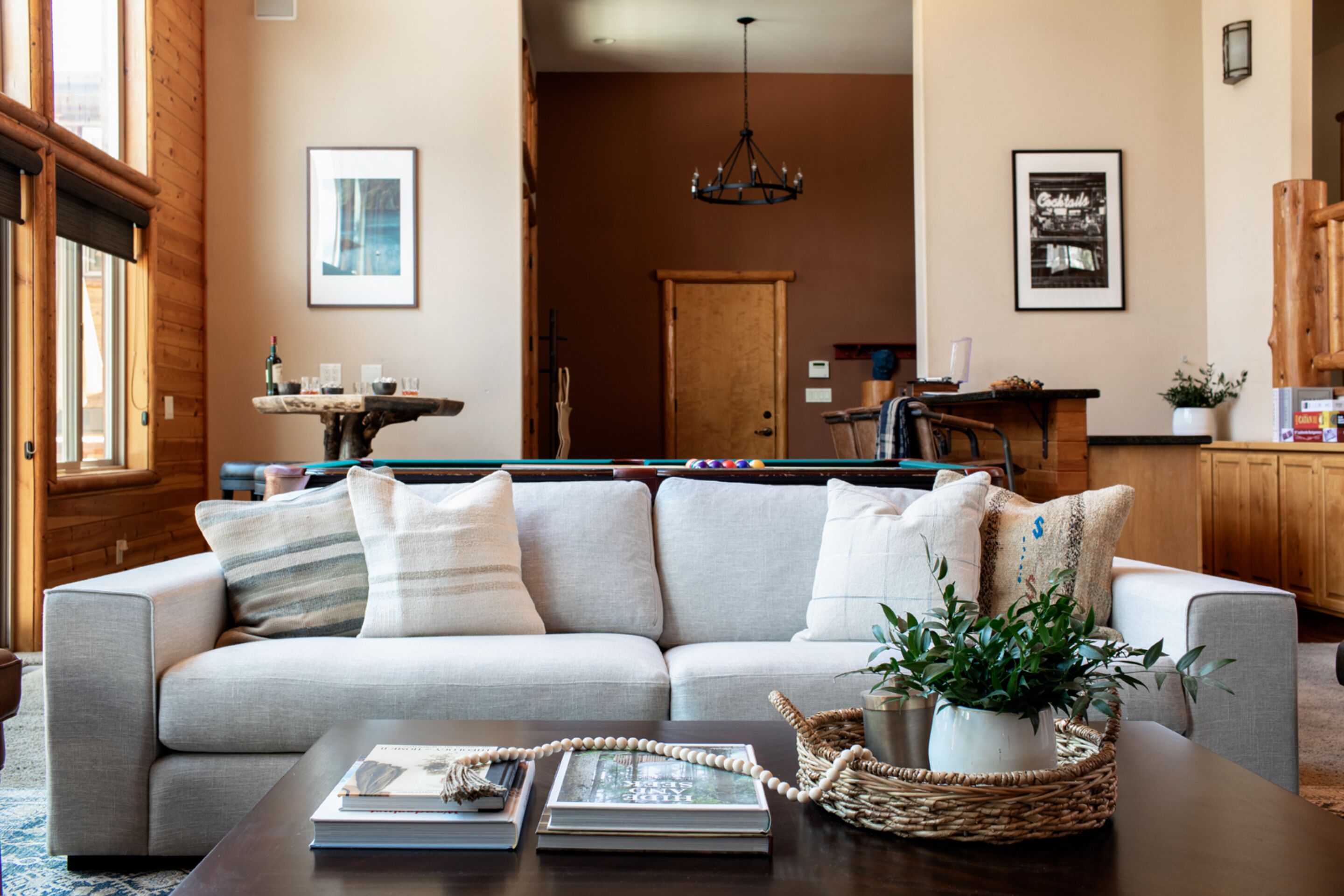 A living room with a sofa, coffee table, and a pool table.