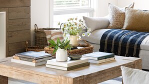 A cozy living room with a wooden coffee table, a wicker basket, a potted plant, and a sofa with a plaid blanket. - Syrah by AvantStay | Hilltop Haven in Sonoma | Private Pool + Patio (Sonoma)
