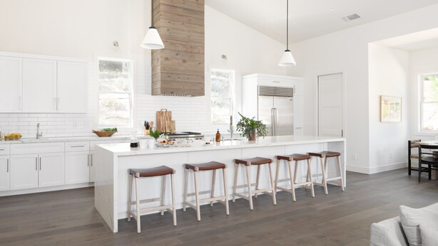 A modern kitchen with white cabinetry, a central island with stools, pendant lighting, and a wooden accent wall. - Syrah by AvantStay | Hilltop Haven in Sonoma | Private Pool + Patio (Sonoma)