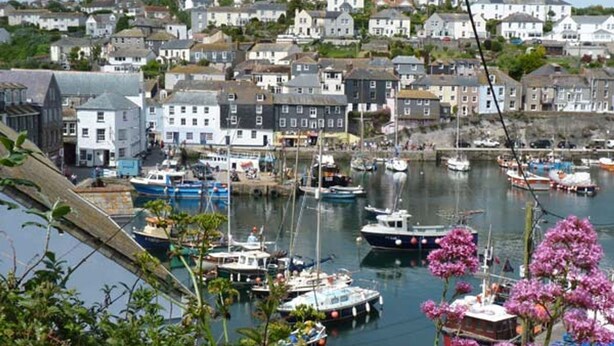 A harbor with boats docked, surrounded by residential buildings. - Rose Cottage (St Austell)