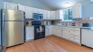 A modern kitchen with white cabinets, stainless steel appliances, and a brick backsplash. - 6 Bedroom sleeps 17 in the Heart of Poconos near everything  (Tobyhanna)