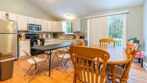 A modern kitchen with white cabinets, a stainless steel refrigerator, a microwave, and a stove. There is a dining table with four wooden chairs. - 6 Bedroom sleeps 17 in the Heart of Poconos near everything  (Tobyhanna)
