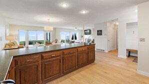 Une cuisine spacieuse dotée d’un grand îlot central, de meubles en bois et offrant une vue sur l’extérieur.