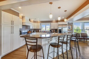 A modern kitchen with a central island, bar stools, and pendant lighting.