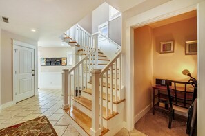 Un intérieur de maison comprenant un escalier, un coin repas et une cuisine.