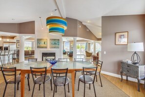 Un vaste espace dédié à la salle à manger, avec une table en verre, des chaises et un luminaire suspendu au design moderne.