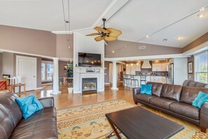 Ein geräumiges Wohnzimmer mit Kamin, Ledersofas und Deckenventilator.
