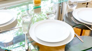 A dining table set with plates, glasses, and cutlery, reflecting a bright, sunny environment. - Bright & Comfortable Angel Apartment (London)