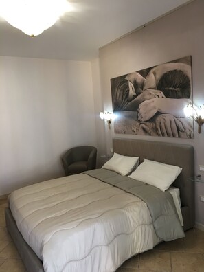 Ein Schlafzimmer mit einem Bett, einem Sessel, einer Wandleuchte und einem Gemälde.