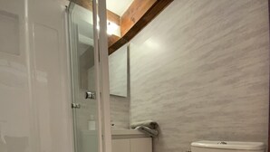 Un baño con cabina de ducha de vidrio, inodoro y lavamanos.