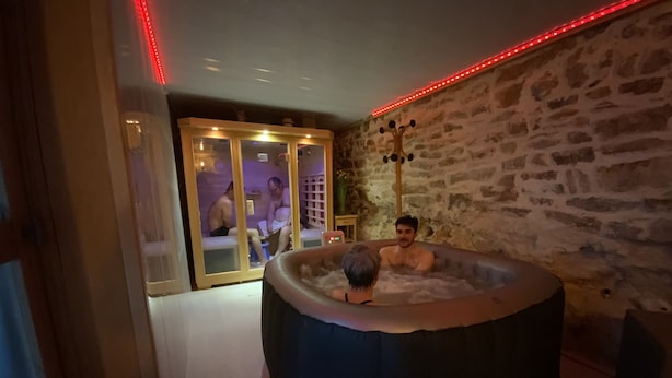 Una habitación con pared de piedra, una bañera grande y un armario de madera.