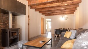 A modern living room with a fireplace, a sofa with fluffy pillows, a wooden coffee table, and a dining area in the background. - VC2 - LUXURY 2 BEDROOM APARTMENT CERRO CATEDRAL (San Carlos de Bariloche)