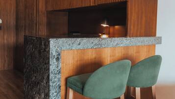 A modern kitchen with wooden cabinets, a granite countertop, and two green bar stools.