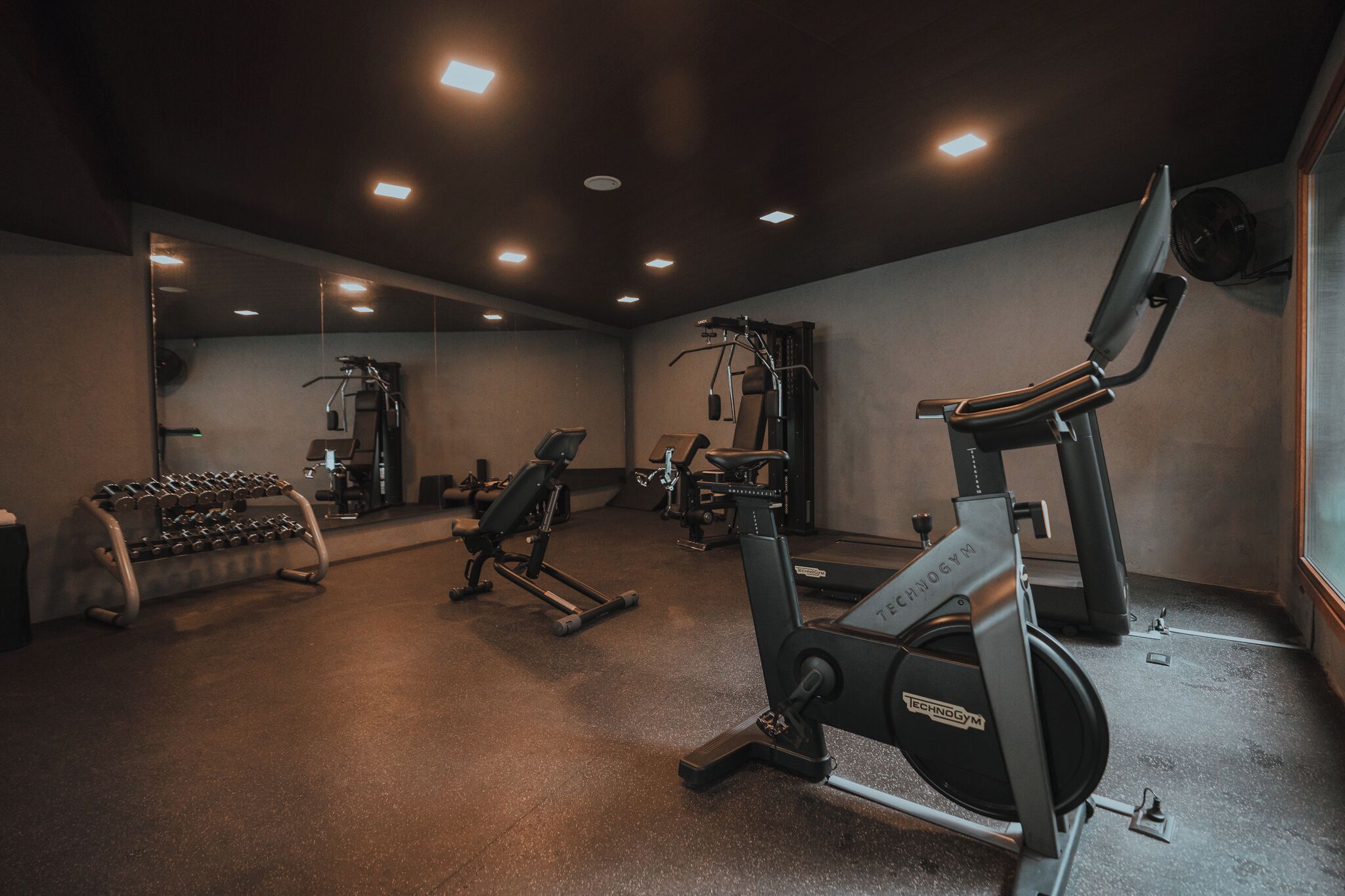 A gym with various exercise equipment, including a treadmill, weight bench, and dumbbells.