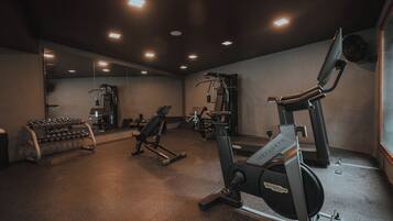 A gym with various exercise equipment, including a treadmill, weight bench, and dumbbells.
