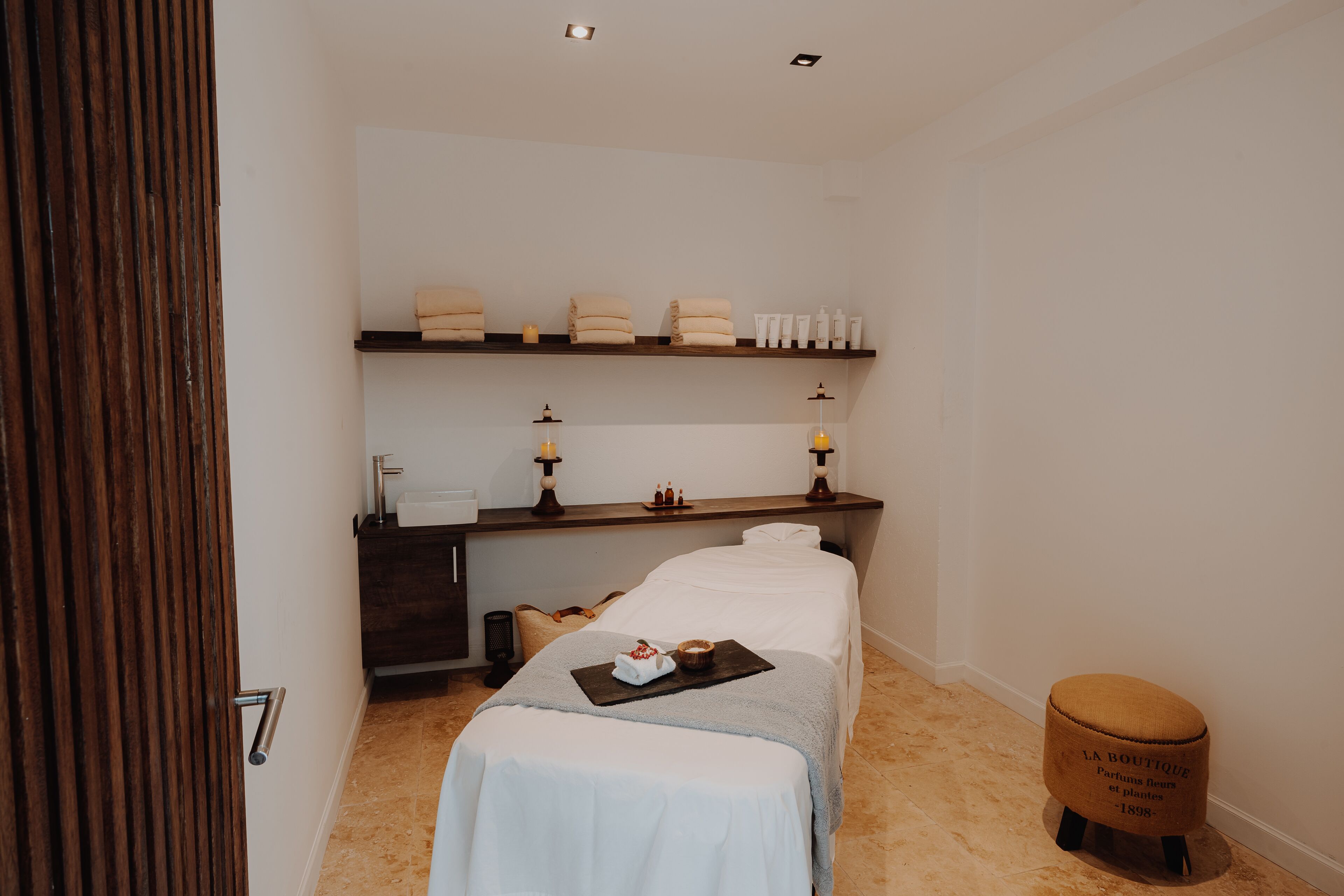 Une chambre à coucher bien rangée, avec un lit, une table de chevet et un petit tabouret.