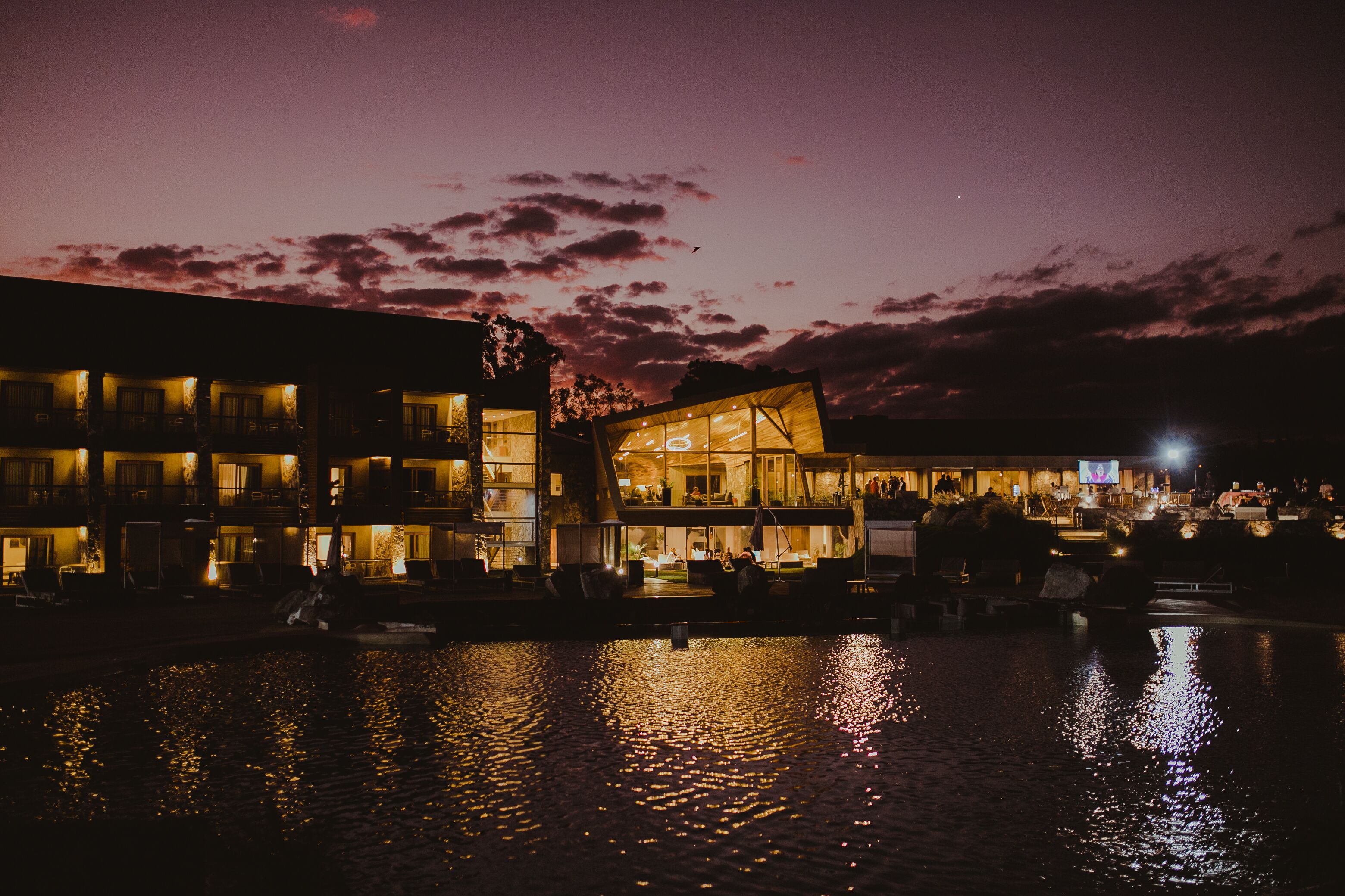 A waterfront hotel with multiple balconies and a reflective water surface.