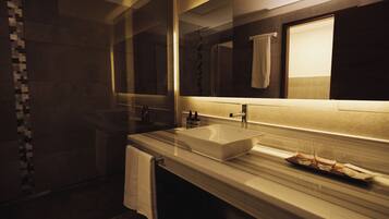 Un baño moderno con un espejo grande, encimera de mármol y cabina de ducha de vidrio.