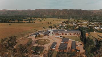 Vista aérea de un moderno complejo de edificios con varias estructuras, rodeado de un paisaje rural con campos y colinas distantes.