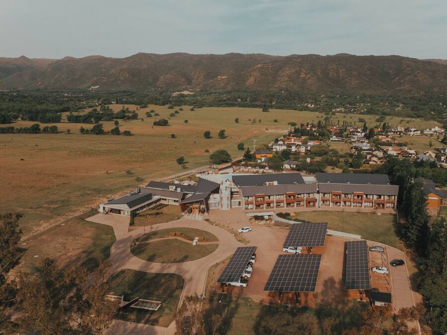 Vista aérea de un moderno complejo de edificios con varias estructuras, rodeado de un paisaje rural con campos y colinas distantes.