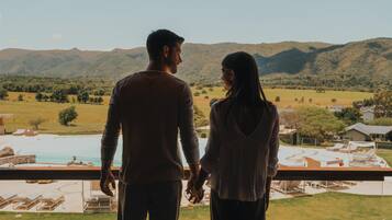 Una pareja de la mano contemplando una piscina y montañas.