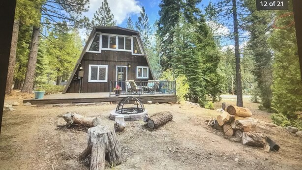 Une cabane dotée d’une terrasse, entourée d’arbres.