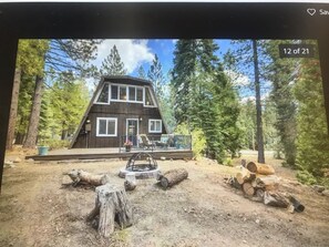 Une cabane dotée d’une terrasse, entourée d’arbres.