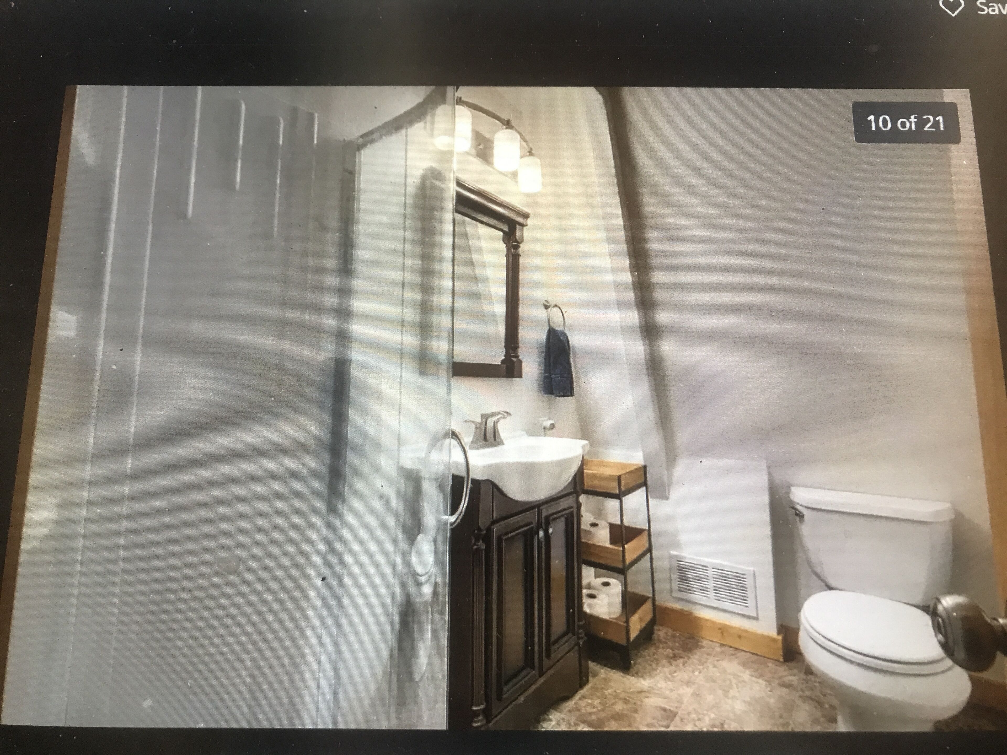 A bathroom with a white sink, dark wooden cabinet, and a white toilet.