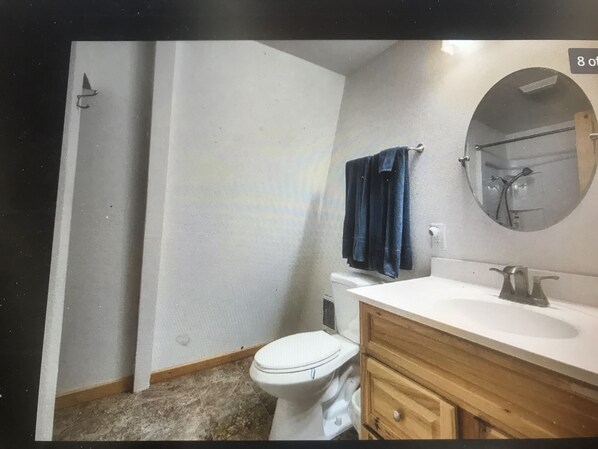 Une salle de bain équipée de toilettes, d’un lavabo, d’un meuble en bois et d’une serviette accrochée au mur.