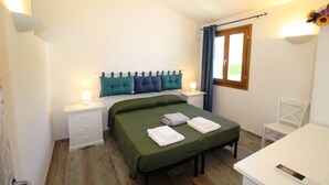 Ein Schlafzimmer mit Bett, Nachttischen, einem Sessel und einem Fenster mit Vorhängen.