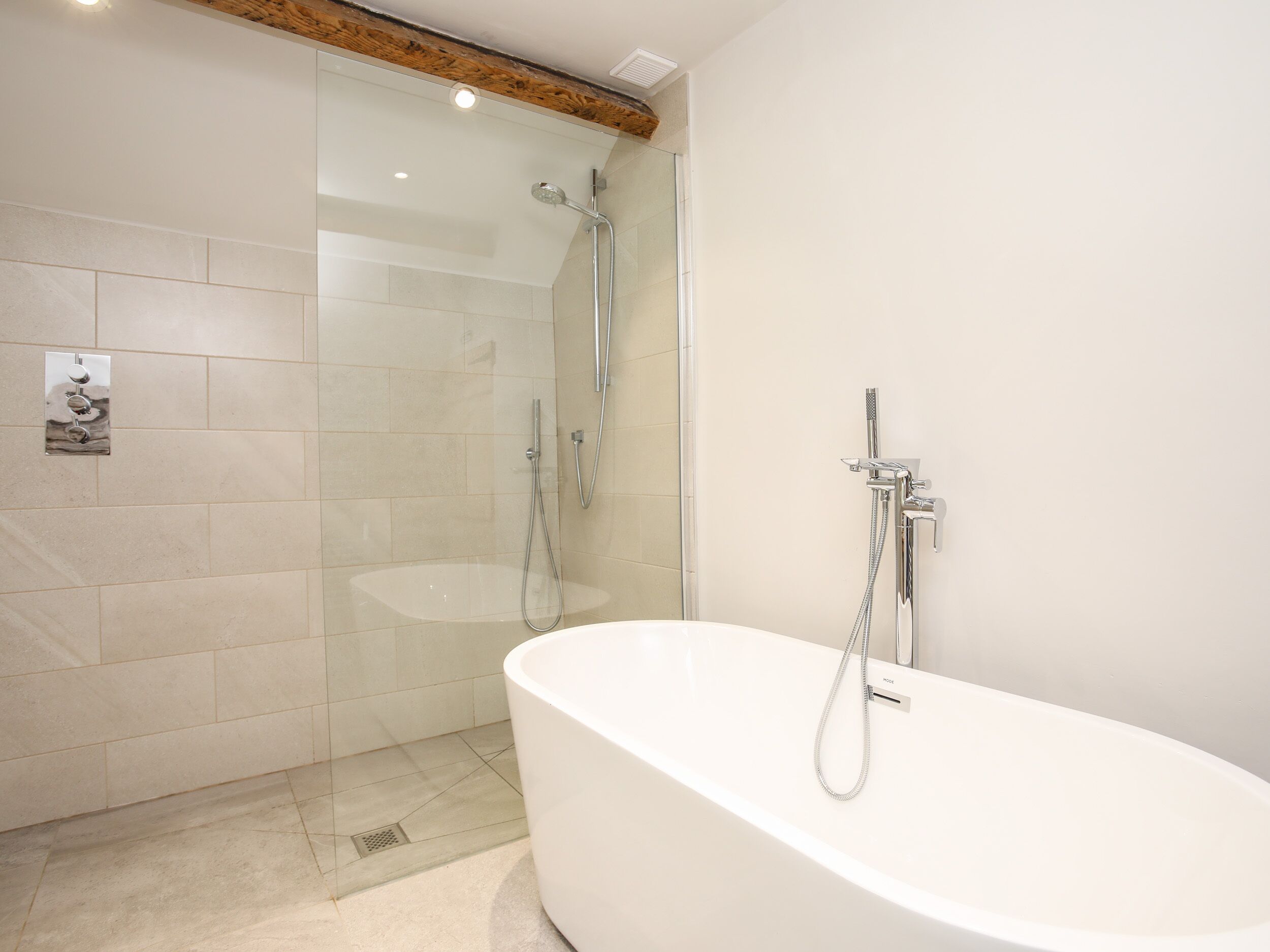 Une salle de bain moderne dotée d’une douche à parois de verre, d’une baignoire sur pied et d’un robinet mural.