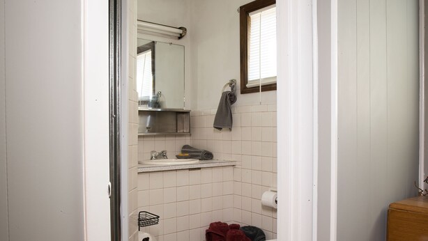 Une petite salle de bain compacte comprenant des toilettes, un lavabo et un espace douche.