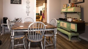 A dining area with a wooden table and metal chairs, a vintage stove, and a kitchen counter with various items. - Triple H Properties (Eminence)