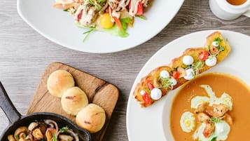Diverse gerechten, waaronder een salade, soep en een braadpan met champignons.
