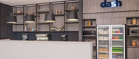 A modern bar area with a reception desk, shelves with bottles, and a refrigerator stocked with beverages.