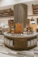 A circular buffet setup with a central wooden column, surrounded by plates and various food items.