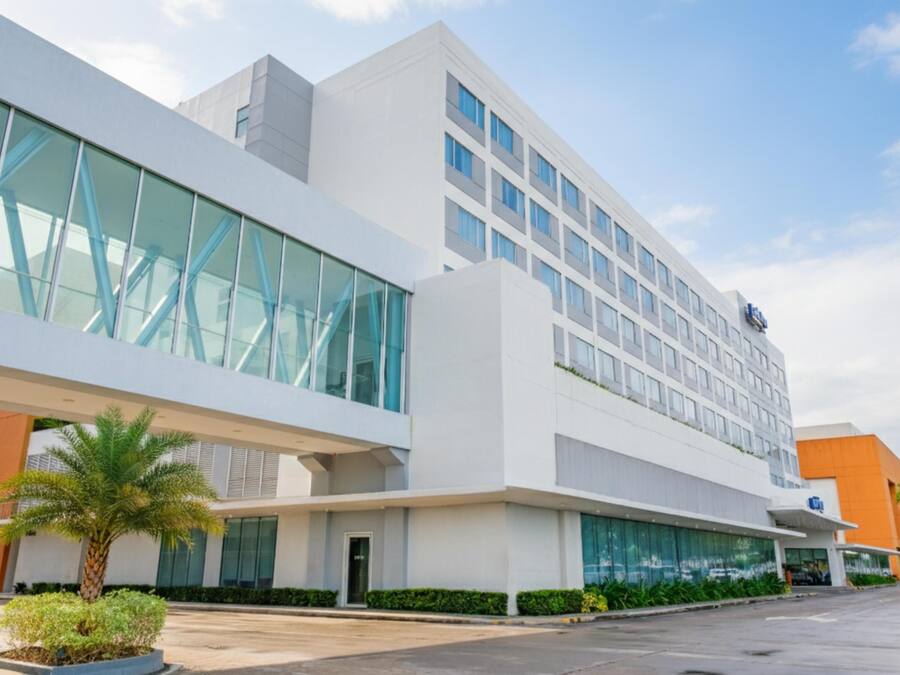 A modern building with large windows, a flat roof, and a palm tree in the foreground.
